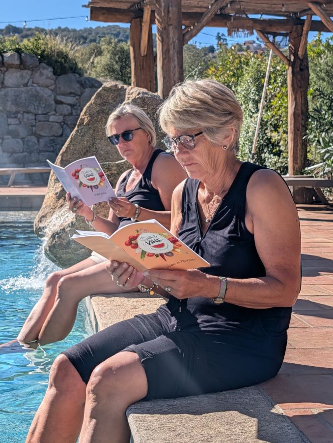 Deux participantes lisent les guides au bord de la piscine